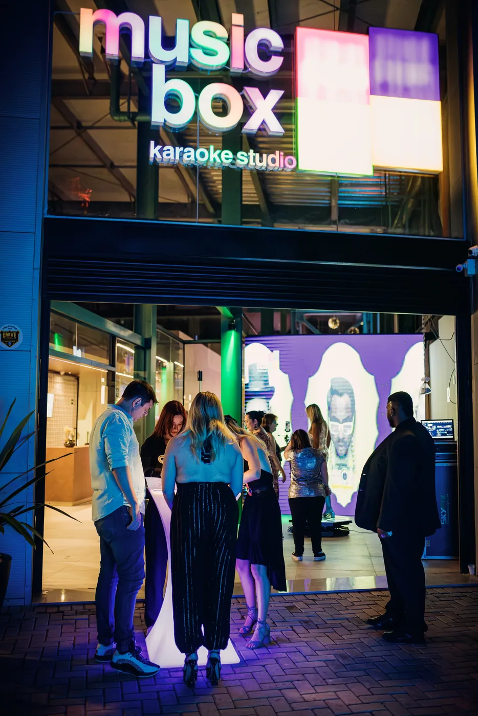 Letreiro em neon com o nome Music Box Karaokê Studio, na fachada de entrada