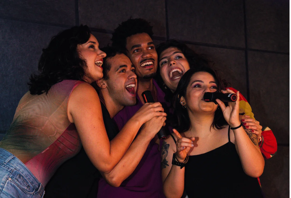 Turma de amigos cantando juntos no Music Box, ambiente iluminado e clima de festa